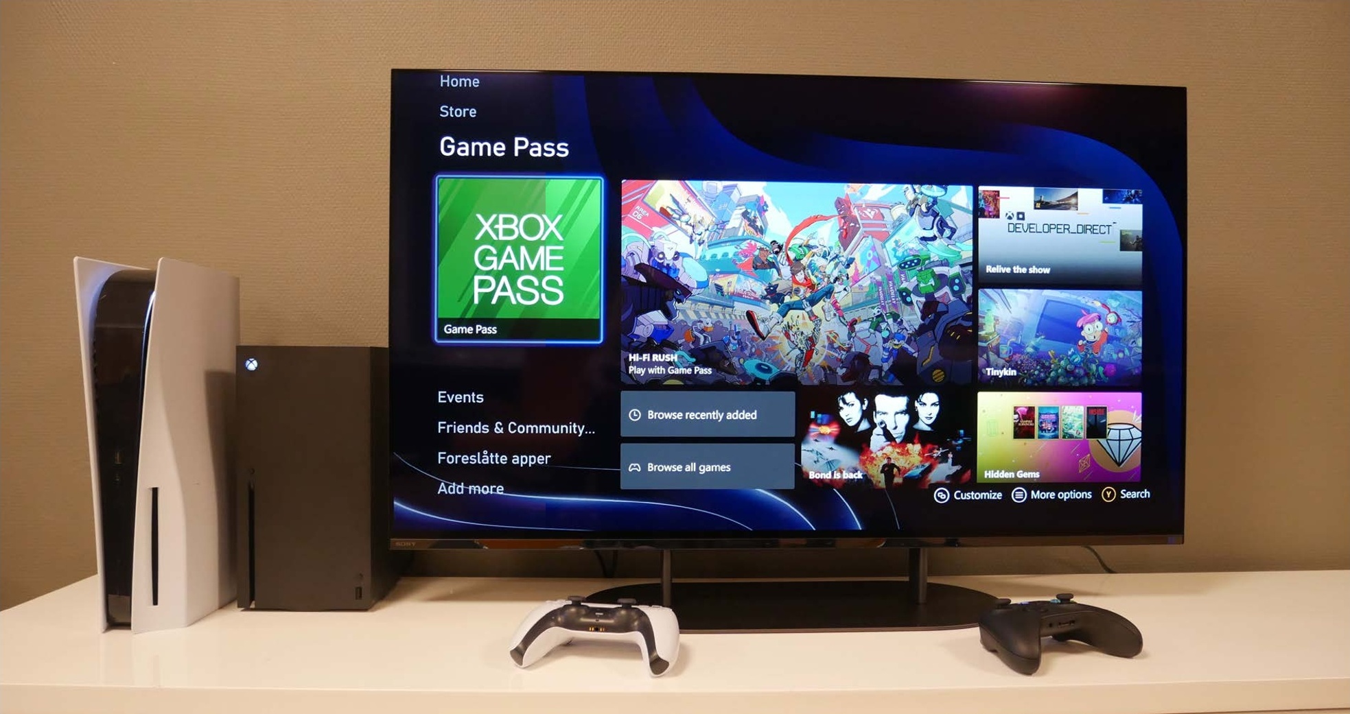 PlayStation 5 e Xbox Series X lado a lado em frente a uma televisão com a interface Xbox Game Pass